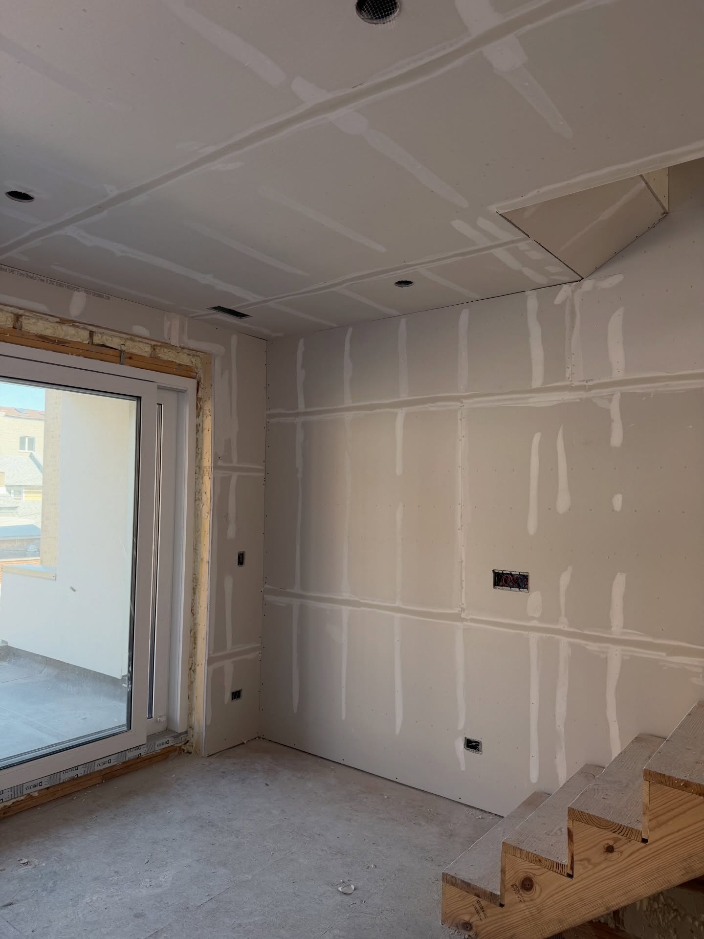 Freshly hung and taped drywall in a room before final finish work