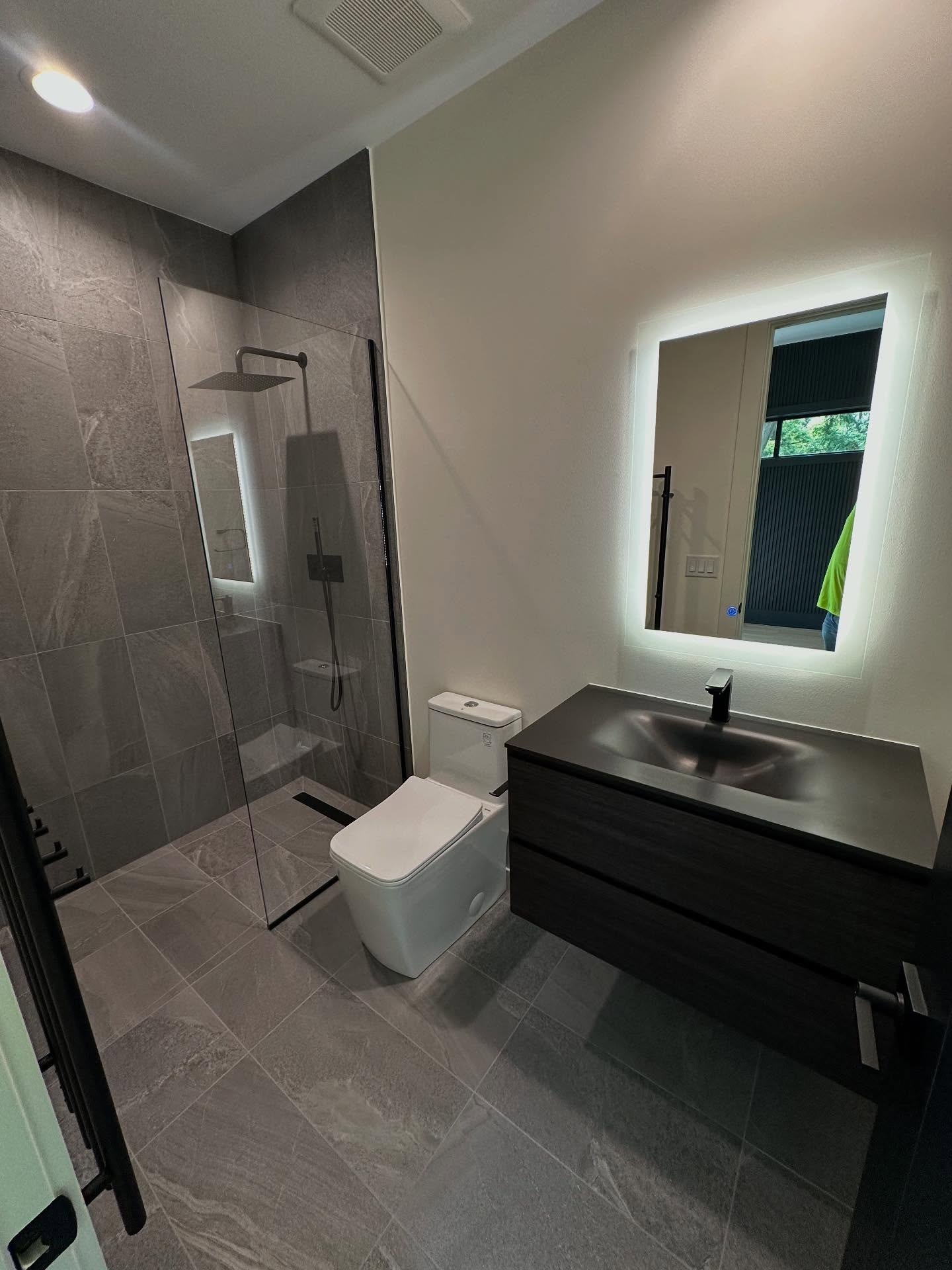 Modern grey stone bathroom with walk-in glass shower
