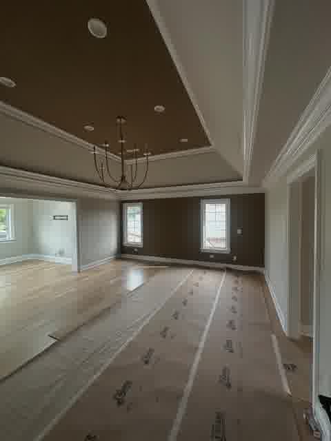 Master bedroom with dark tray ceiling, crown molding and chandelier, floor protection still down, Bloomingdale