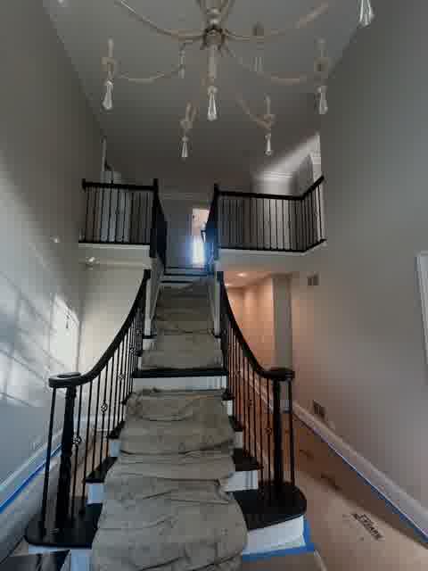 Grand staircase painting in progress with drop cloths and chandelier, Bloomingdale