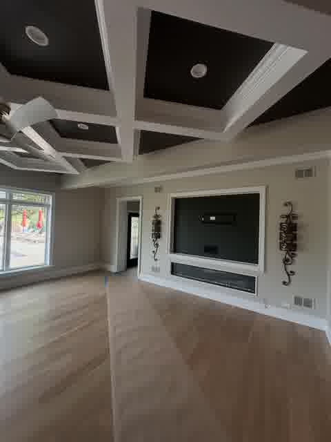 Coffered ceiling with black panels and white beams, fireplace niche with TV mount and iron sconces, pool view, Bloomingdale