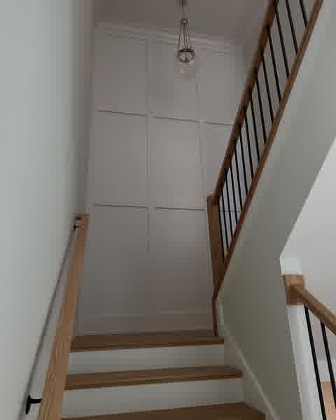 Staircase with white panel molding accent wall, wood treads and glass pendant, Clarendon Hills
