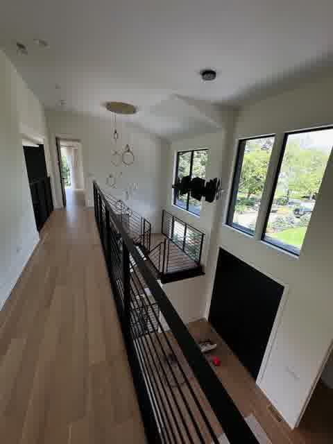 Upper hallway overlook with ring pendant lights, vaulted ceiling and black railings, Oak Brook
