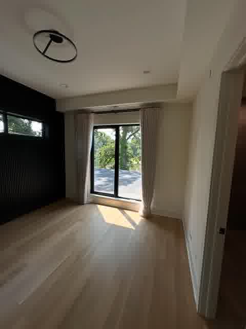 Dark bedroom with black fluted wall panel and sheer curtain slider to balcony, Oak Brook