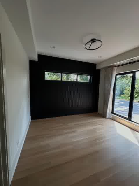 Bedroom with black fluted accent wall, minimalist ring light and floor-to-ceiling slider, Oak Brook
