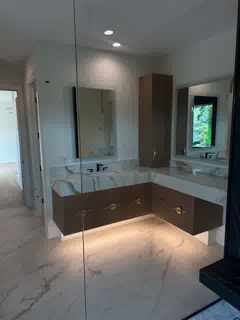L-shaped marble vanity with fluted taupe drawers, brass pulls and LED glow, Oak Brook